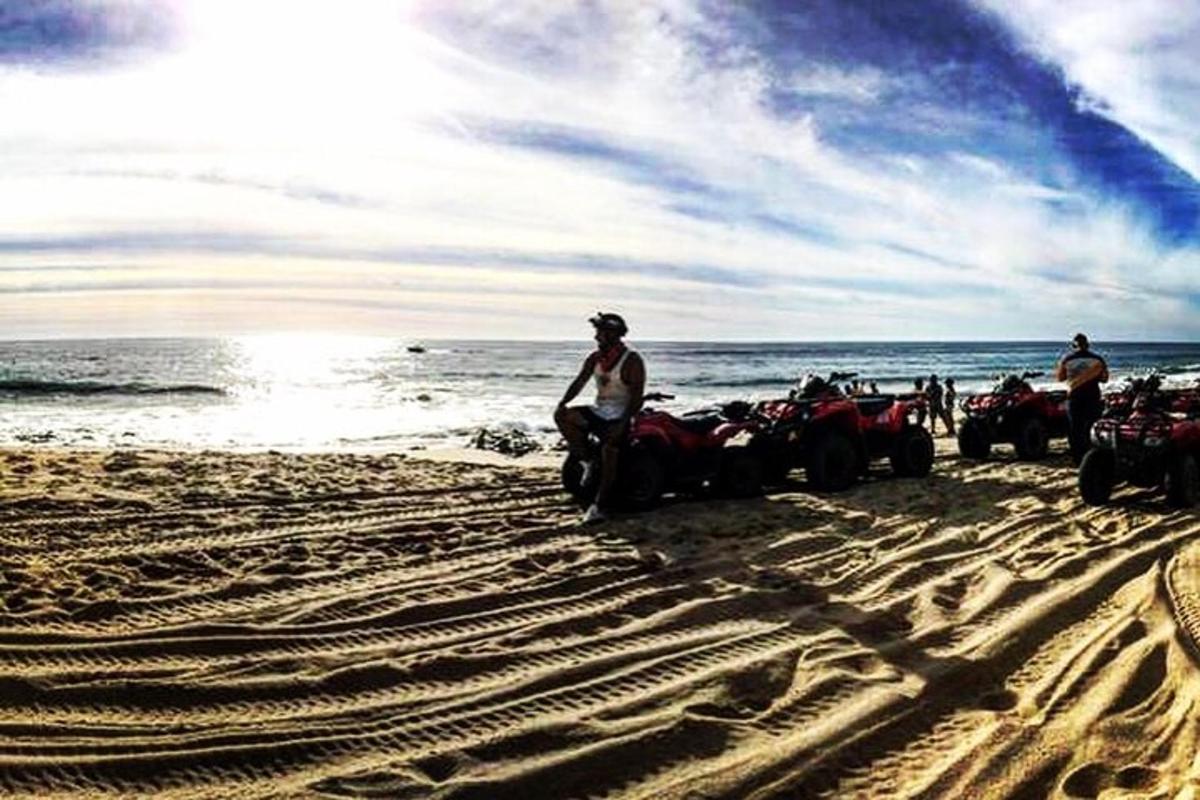 a group of people standing on the beach with atvs