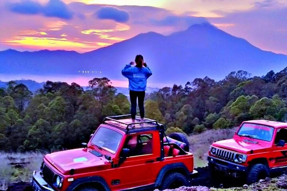 a person standing on the roof of a red jeep