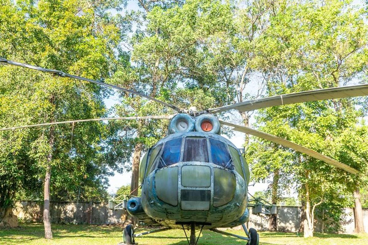 egy zöld helikopter ül a fűben egy mezőn