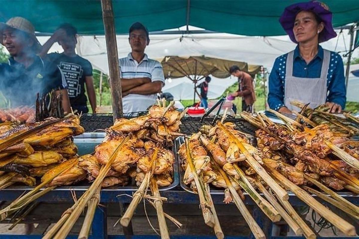 skupina lidí stojících kolem grilu s jídlem