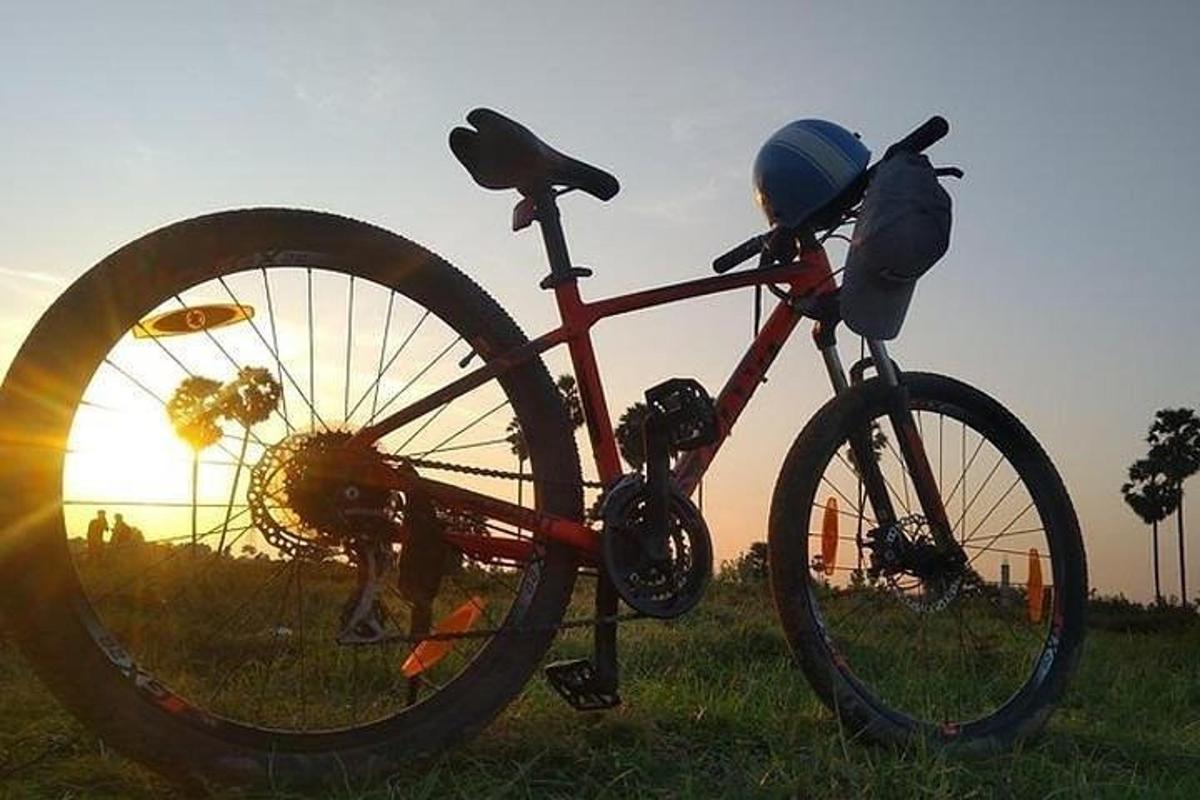 Una bicicleta estacionada en un campo con el atardecer de fondo