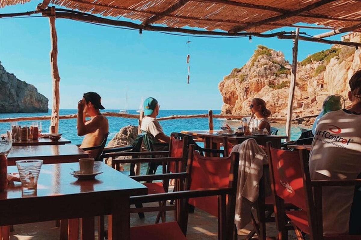 μια ομάδα ανθρώπων που κάθονται σε τραπέζια κοντά στον ωκεανό