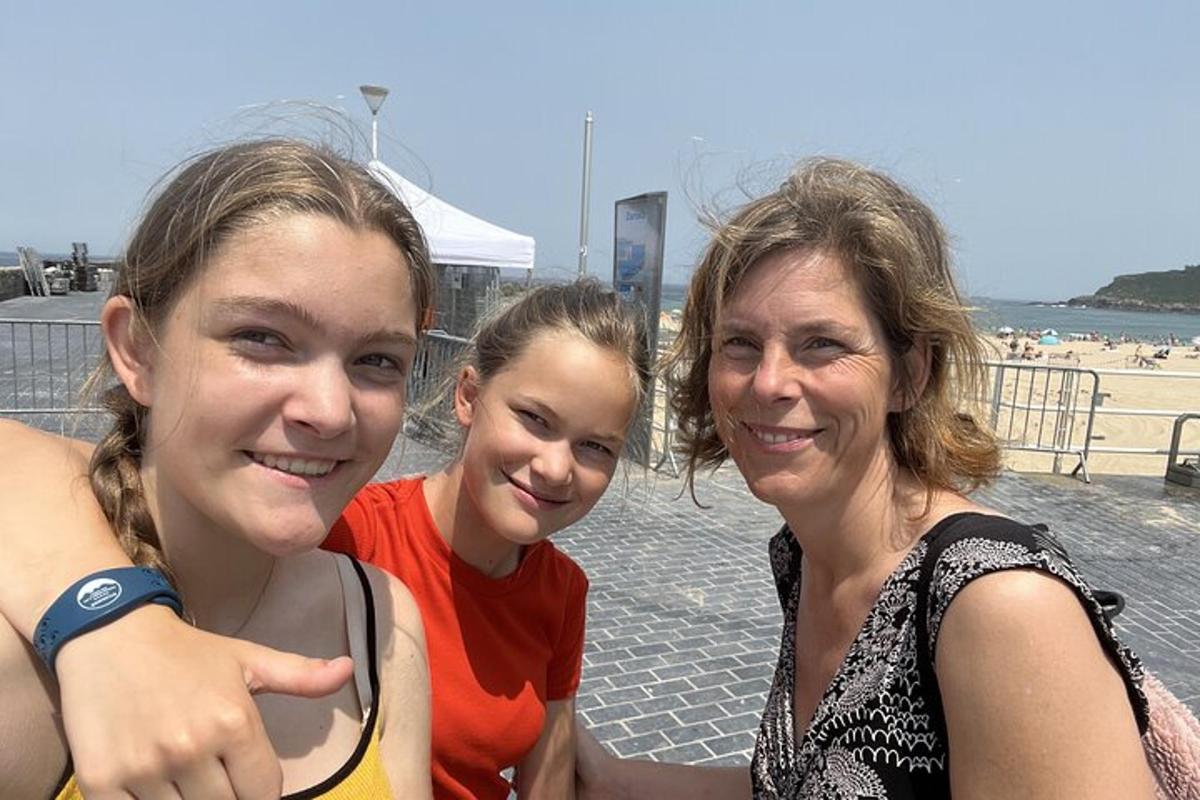 duas meninas e uma mulher posando para uma foto na praia