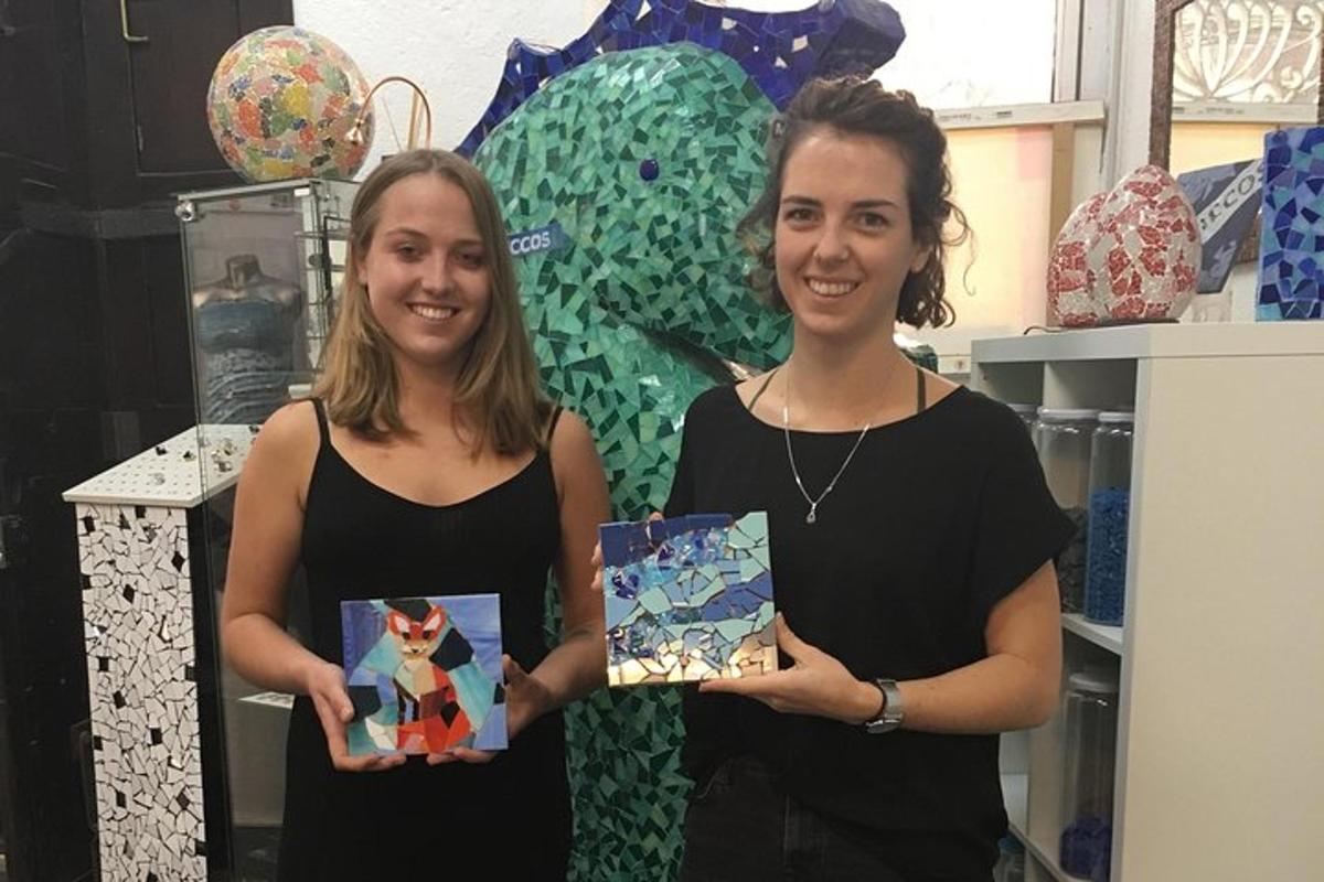 Dos mujeres paradas una al lado de la otra sosteniendo pinturas