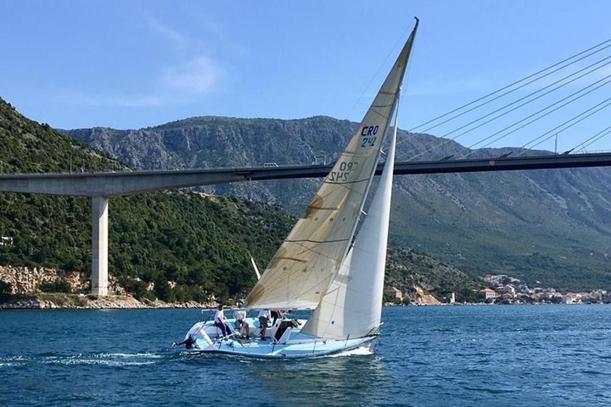 egy vitorlás a vízben egy híd közelében