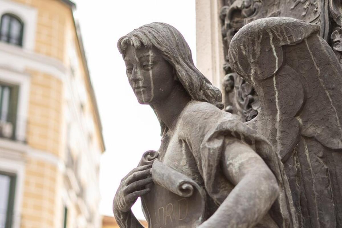 en staty av en ängel som håller en skylt