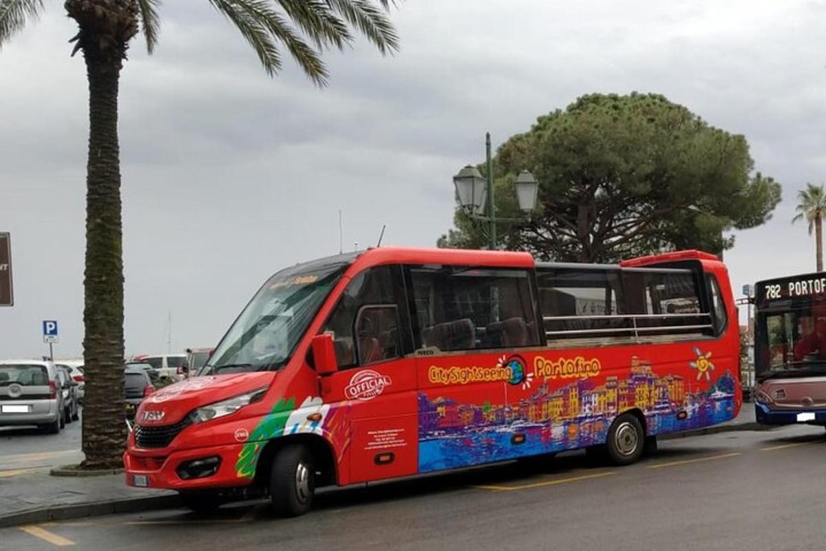 ένα κόκκινο λεωφορείο που οδηγεί σε έναν δρόμο δίπλα σε έναν φοίνικα