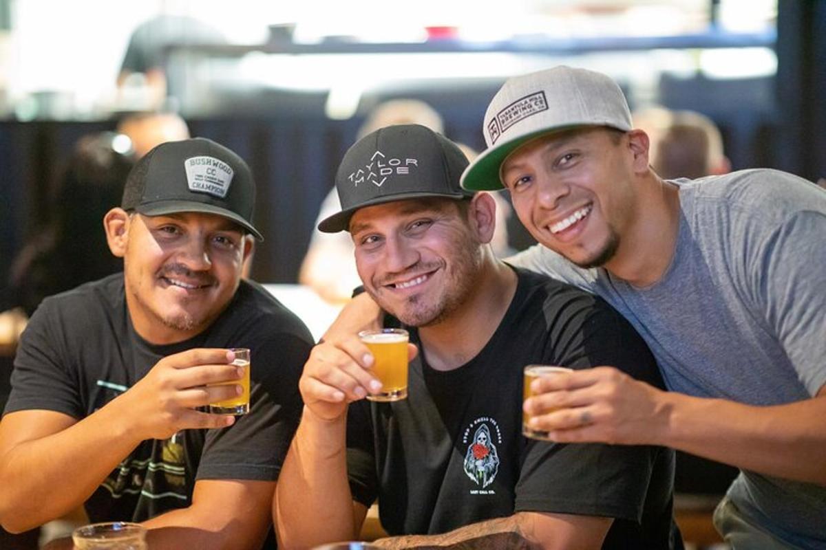 Tres hombres sentados en una mesa bebiendo cerveza