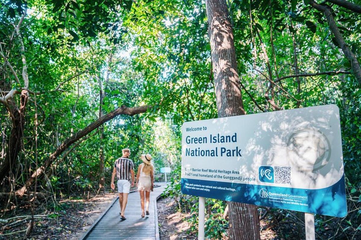 a man and woman walking on a wooden path next to a sign