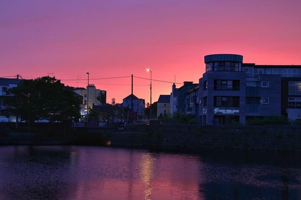 a sunset over a city with a river and buildings
