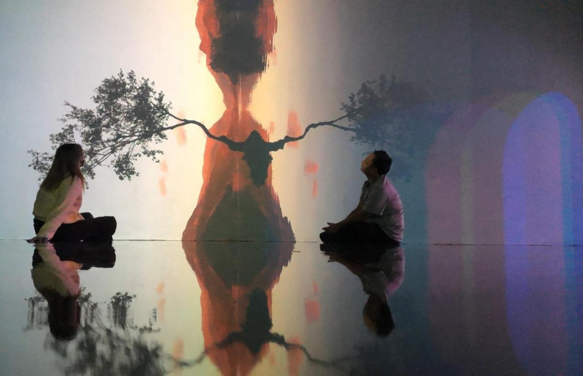 a shadow of two women sitting in front of a wall
