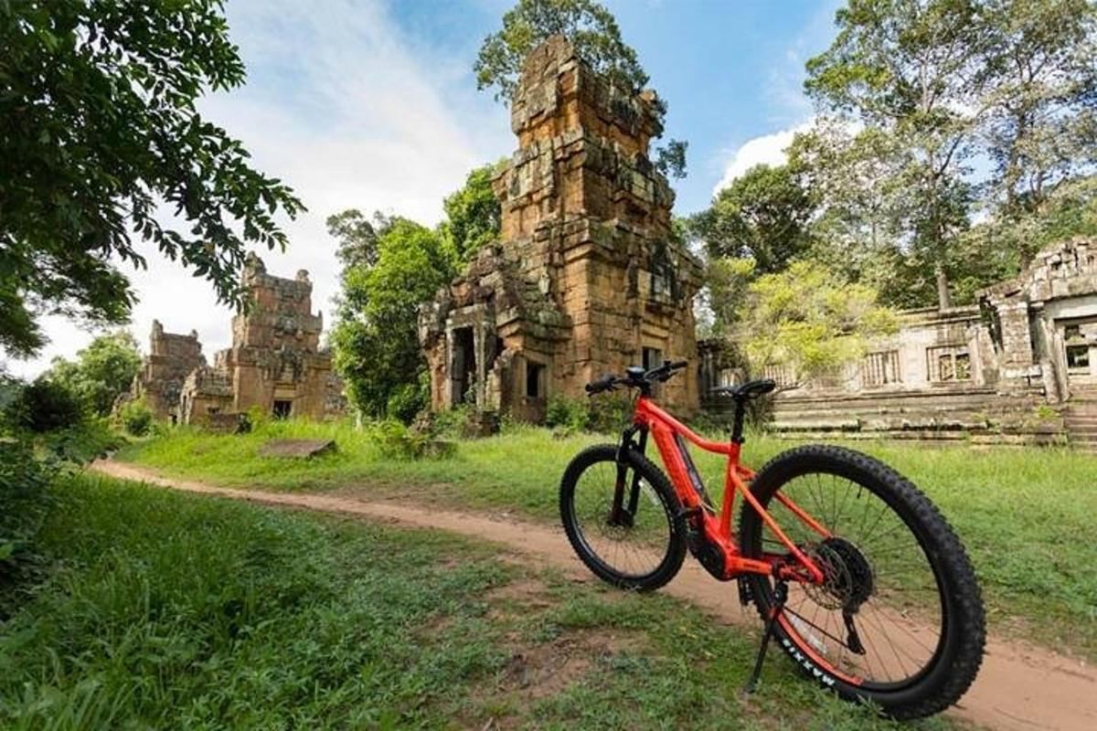 isang pulang bisikleta na nakaparada sa isang maruming kalsada malapit sa isang gusali