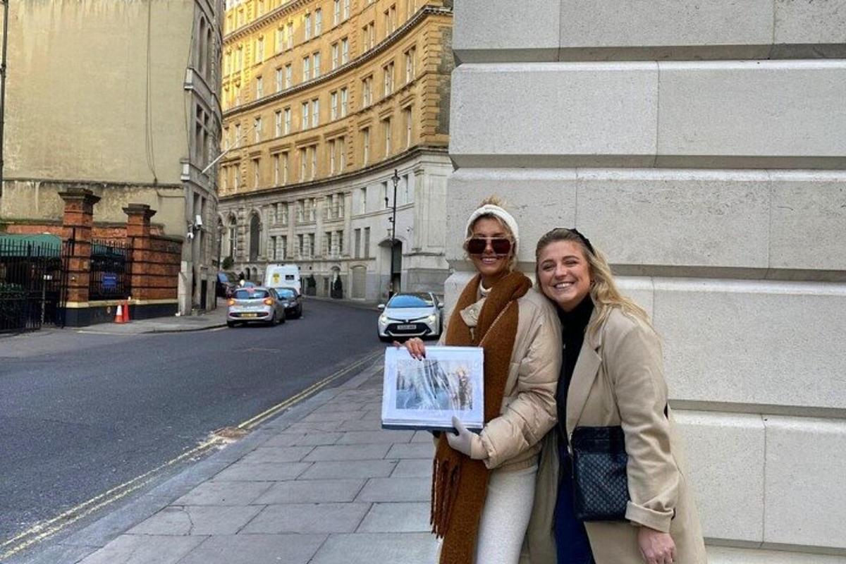 dua wanita berdiri di atas jalan sambil memegang gambar