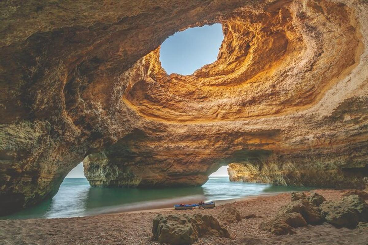 a cave on the beach with a boat in the water
