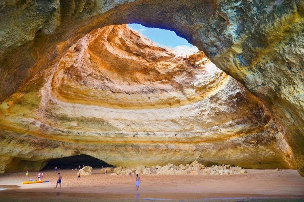un gruppo di persone in piedi su una spiaggia sotto una grotta