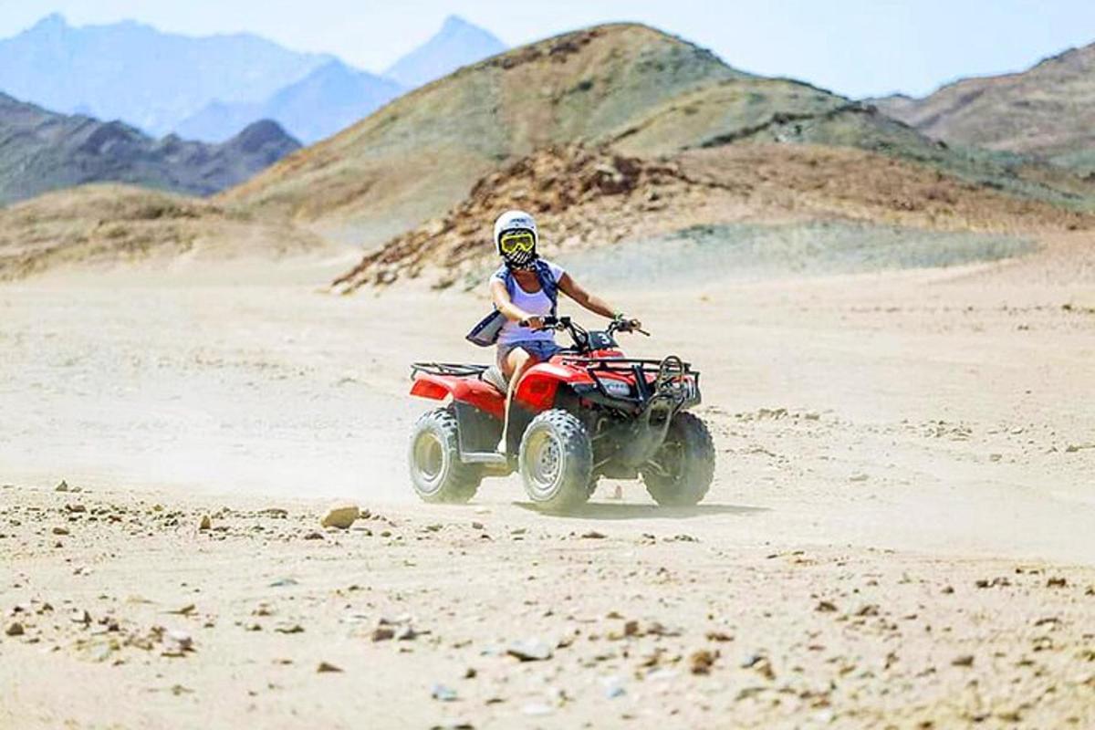 seseorang mengendarai sepeda quad di padang pasir