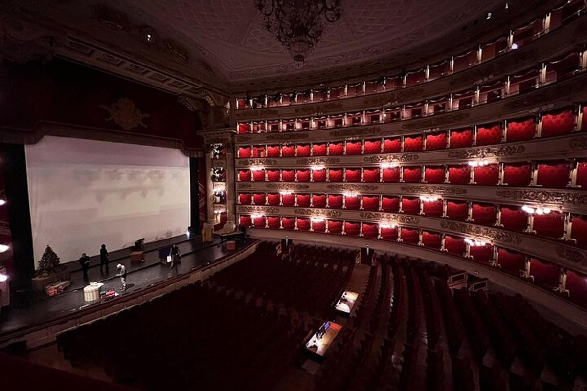 an empty auditorium with red chairs and a screen