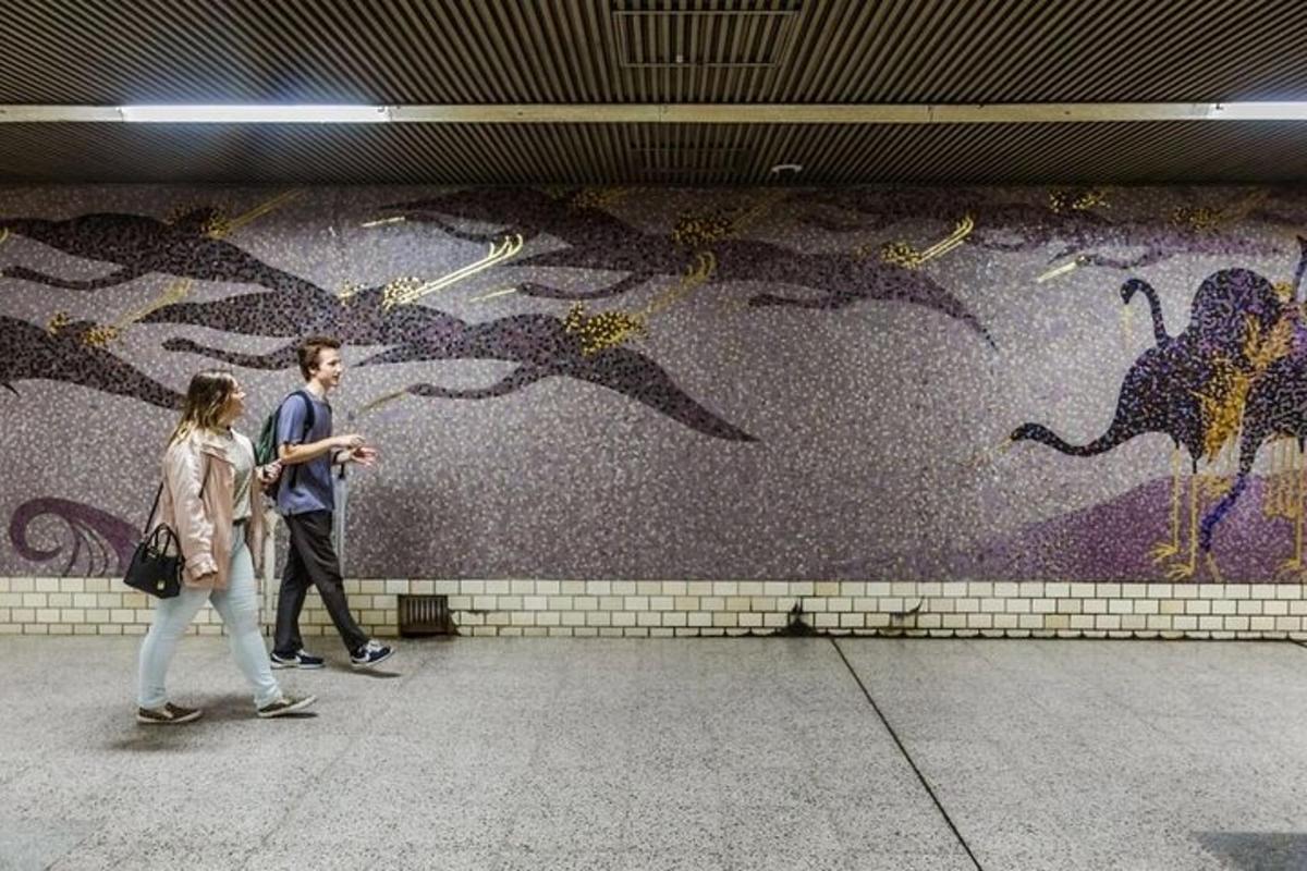 Moški in ženska hodita mimo zidu s poslikavo ptic