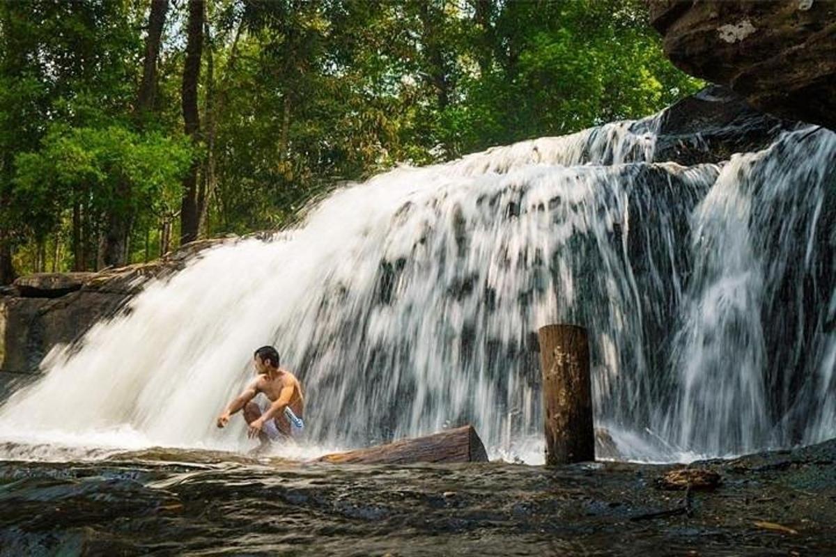 un uomo è in piedi davanti a una cascata