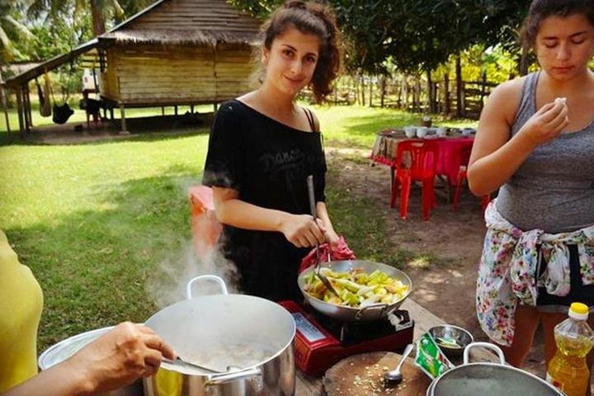 seorang wanita memasak makanan di wajan di atas panggangan