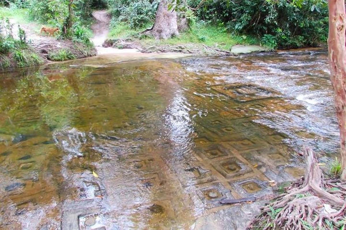 a dirt road with a grate in the water