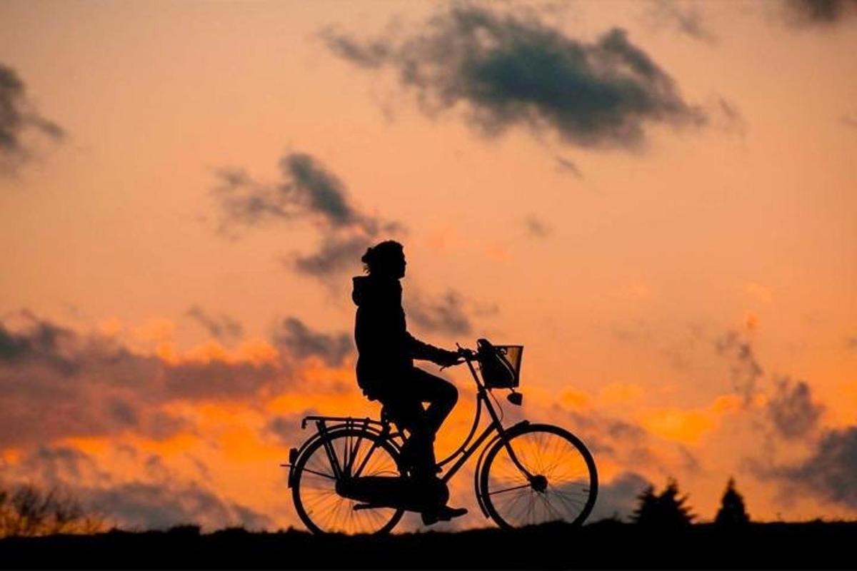 osoba jazdiaca na bicykli pred západom slnka