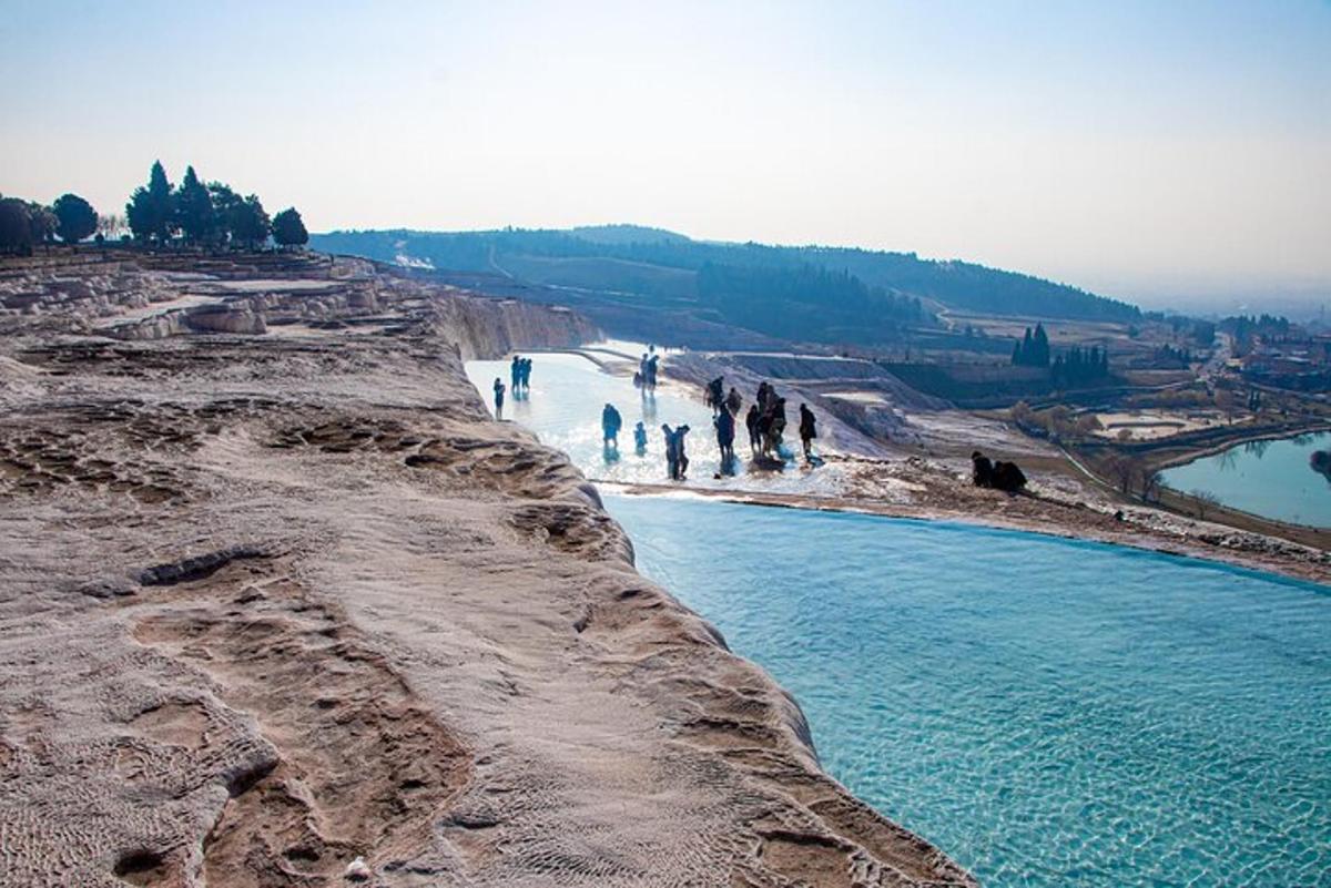 un gruppo di persone che camminano su una spiaggia vicino a uno specchio d'acqua