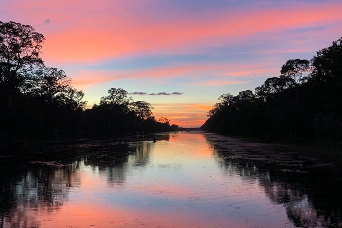 um rio com árvores e um pôr do sol ao fundo