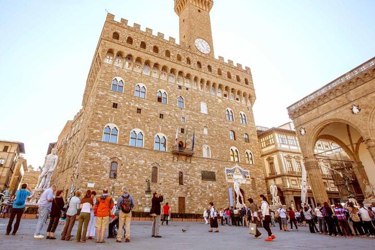 un gruppo di persone in piedi davanti a un edificio con una torre dell'orologio