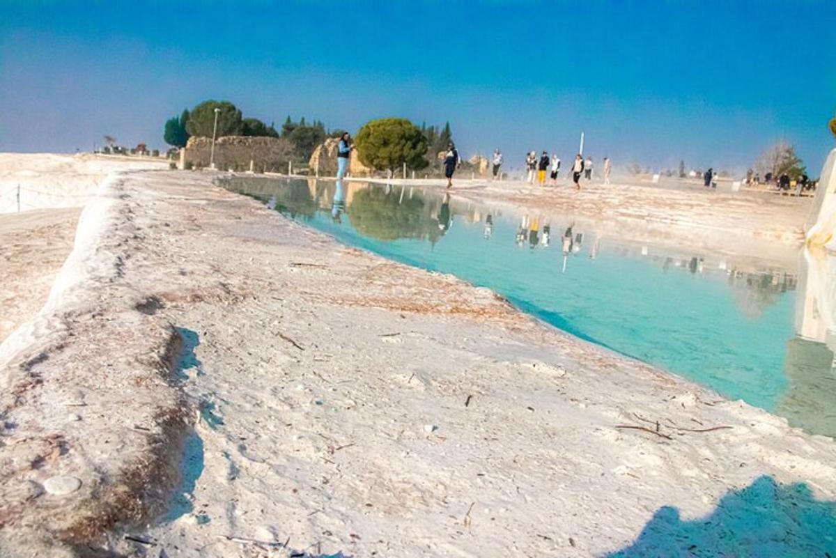 um grupo de pessoas caminhando em uma praia com água azul
