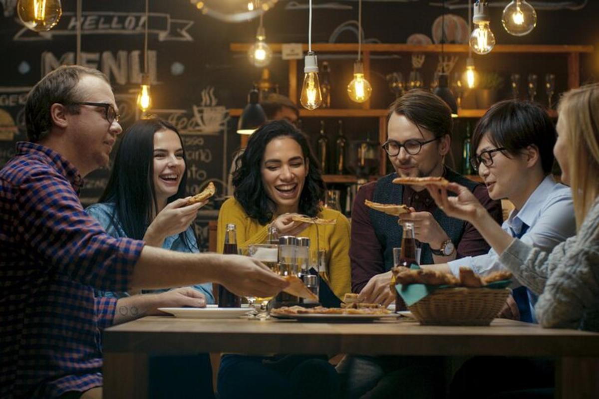 a group of people sitting around a table eating pizza