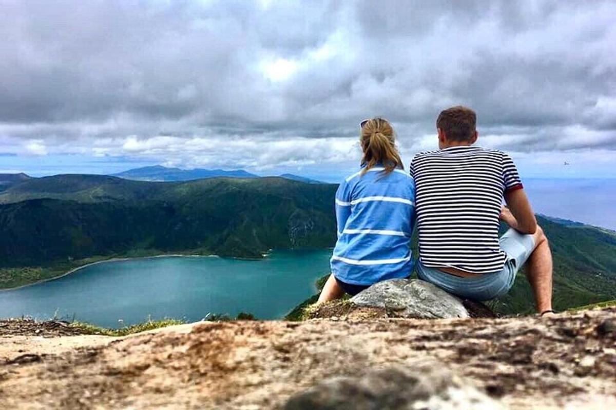 Pár sedící na vrcholu hory s výhledem na jezero