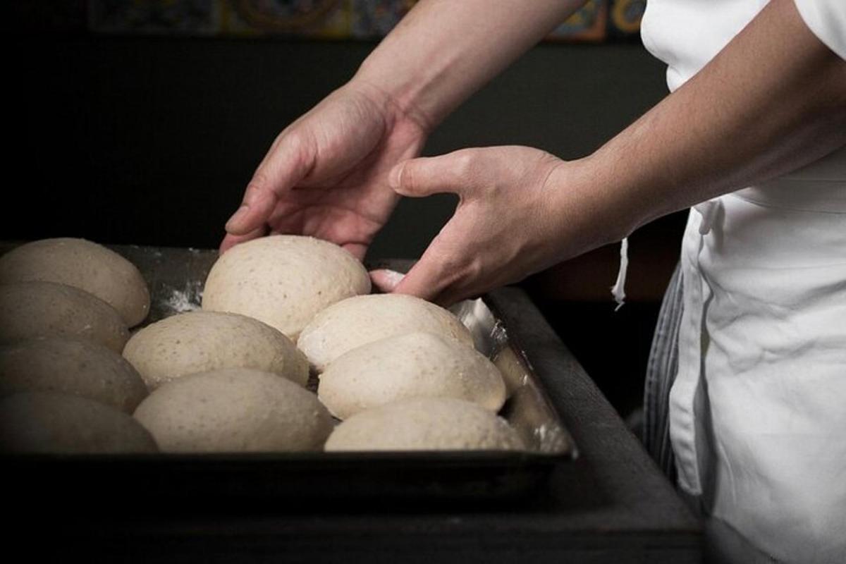 una persona in piedi accanto a un vassoio di pasta