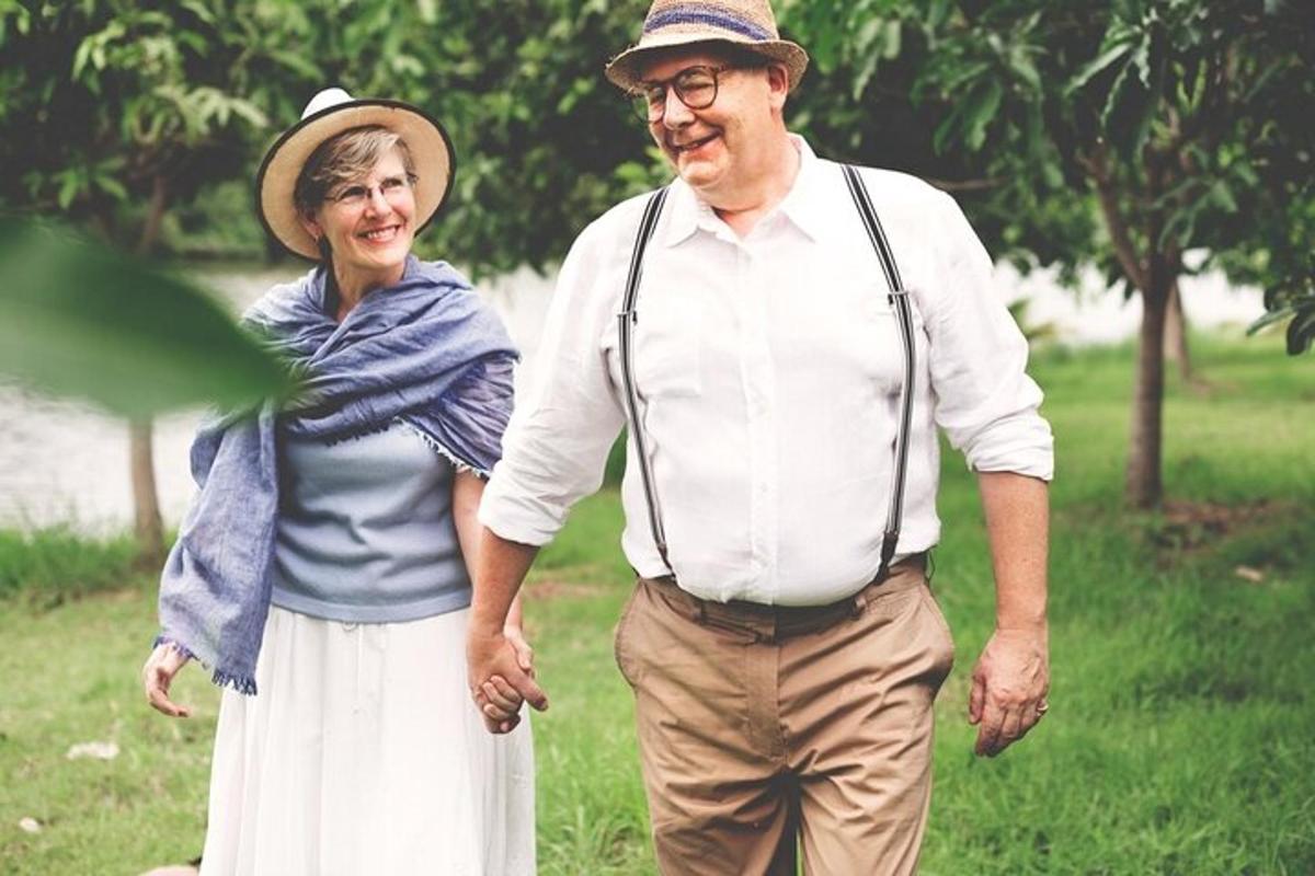 an older man and woman walking through a park
