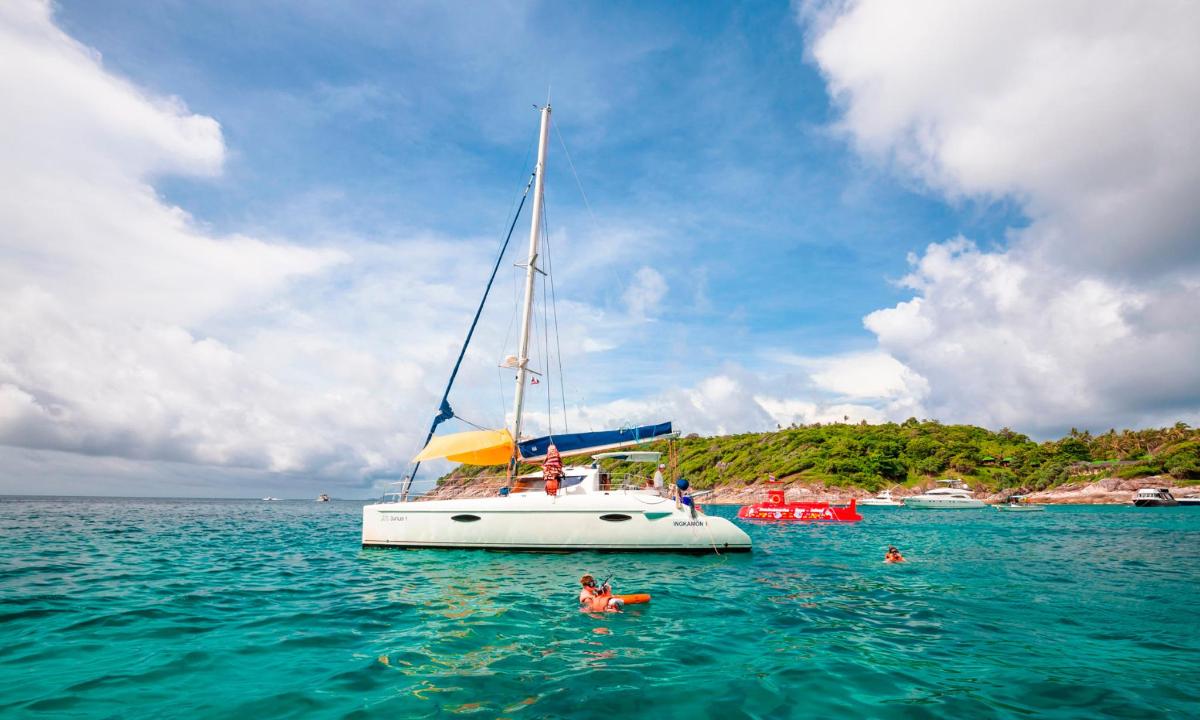 a group of people swimming in the water next to a sail boat