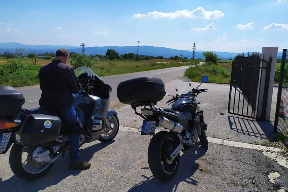 moški, ki sedi na motorju ob robu ceste