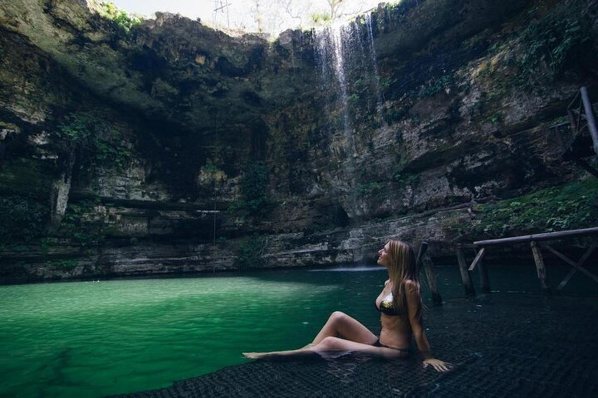 uma mulher sentada na água perto de uma cachoeira