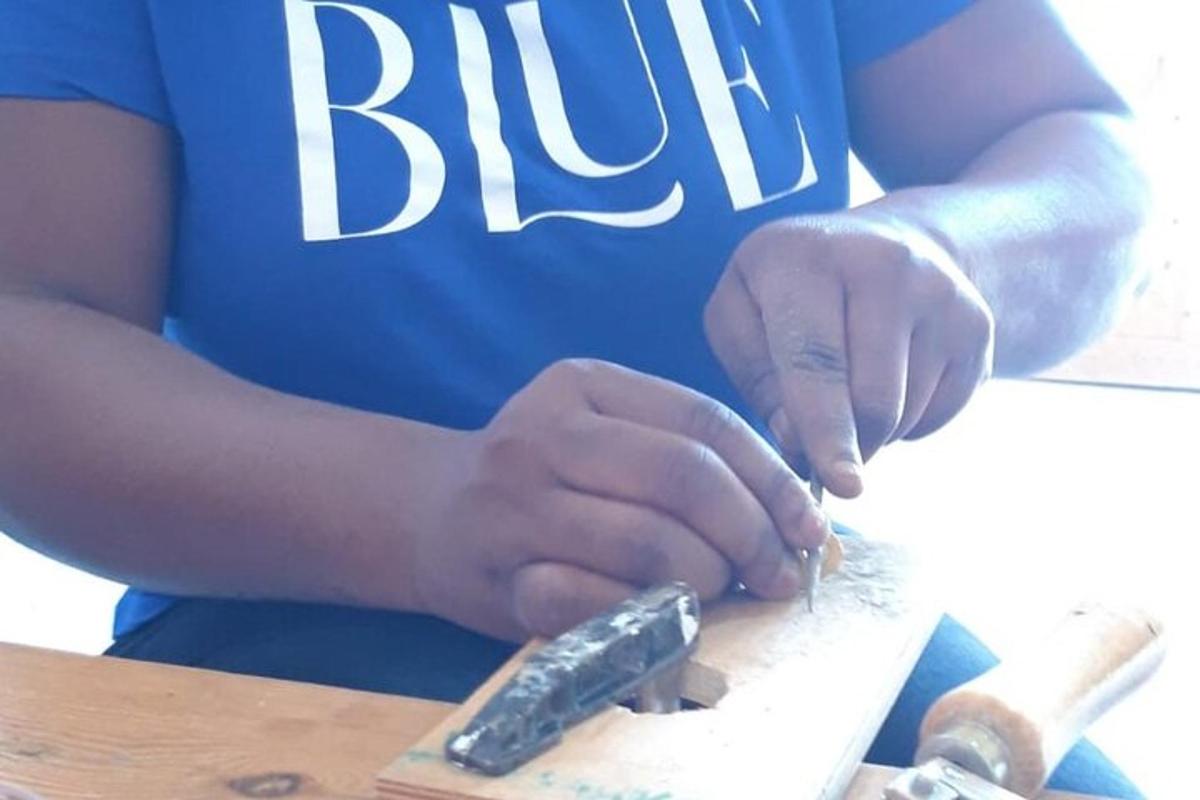 a person in a blue shirt cutting a piece of wood