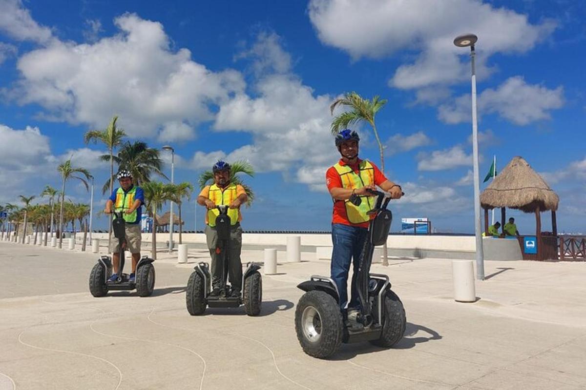 two men in yellow vests riding segways on the beach