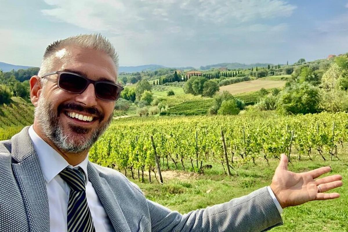 a man in a suit and sunglasses pointing at a vineyard
