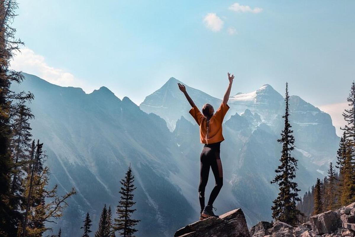 eine Person, die mit erhobenen Händen auf einem Berggipfel steht