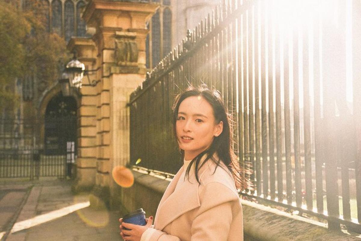 seorang wanita berdiri di sebelah pagar sambil memegang minuman