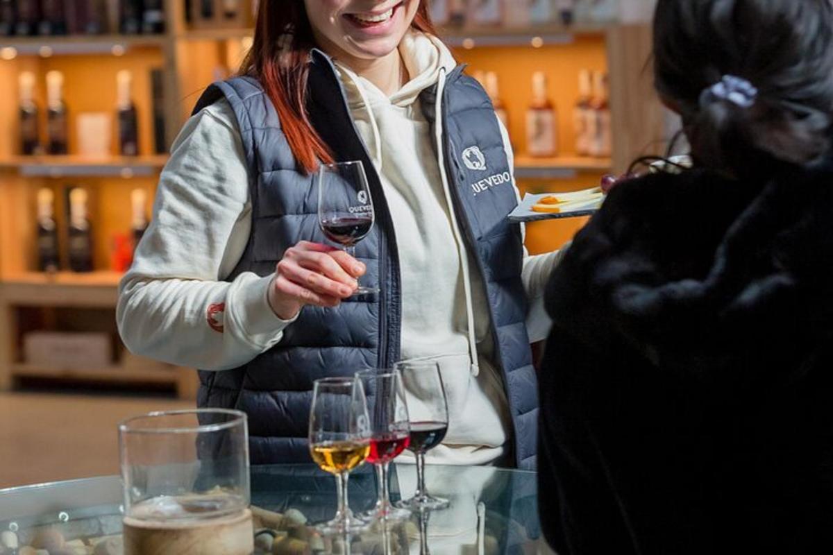 uma mulher em pé diante de uma mesa segurando uma taça de vinho