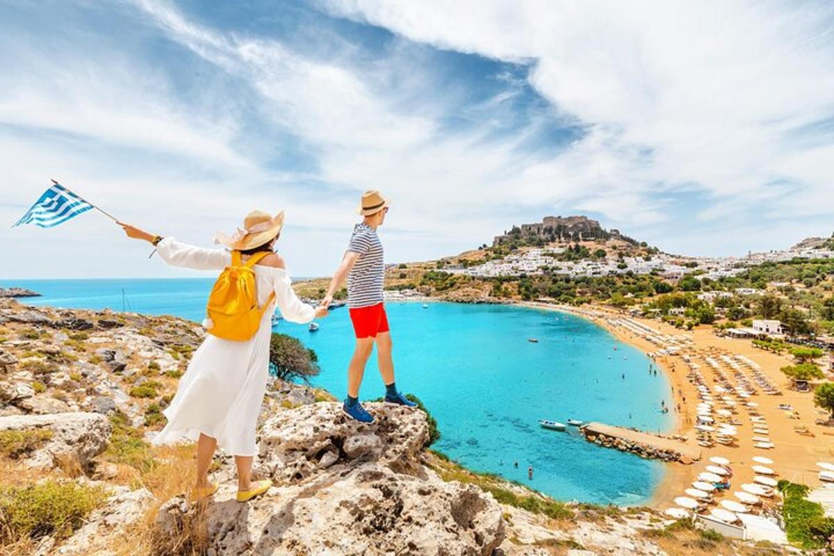 un uomo e una donna in piedi sulla cima di una collina con una spiaggia