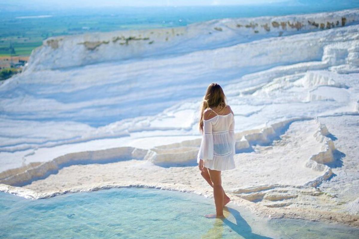 Una mujer con un vestido blanco parada en el agua.