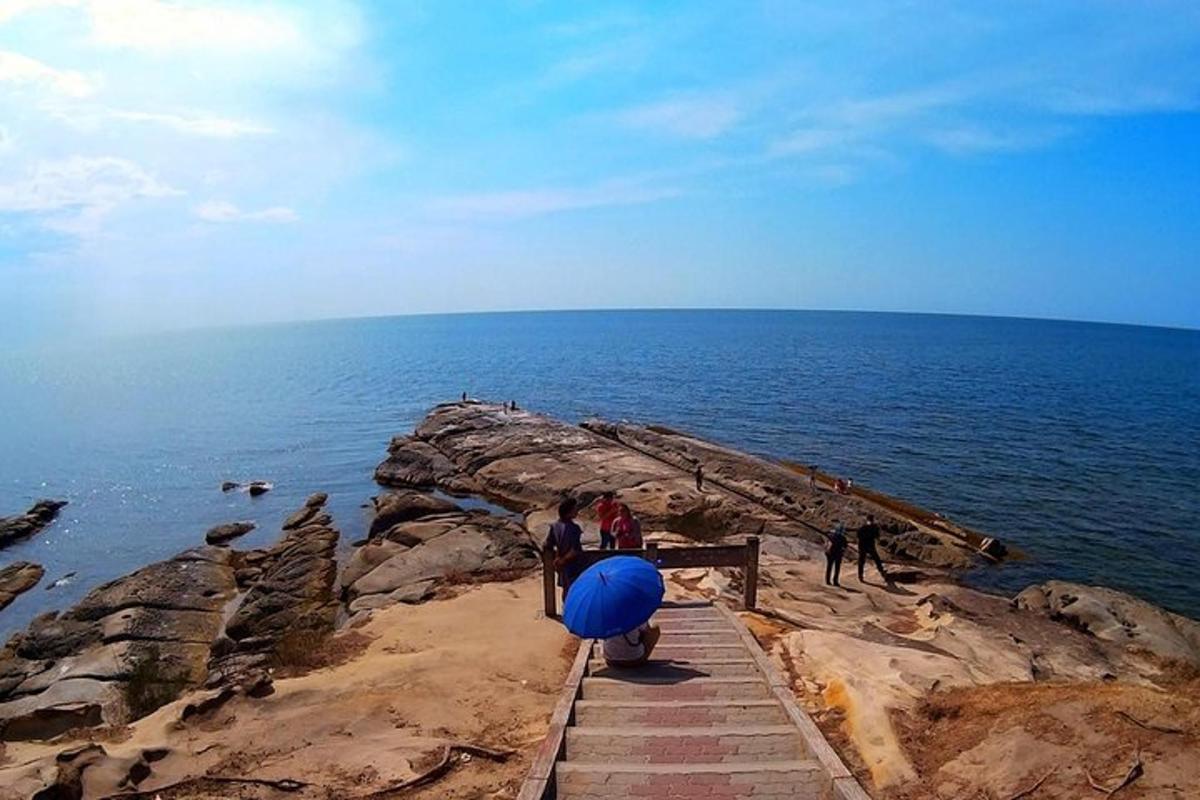 skupina ljudi, ki stojijo na pečini blizu oceana