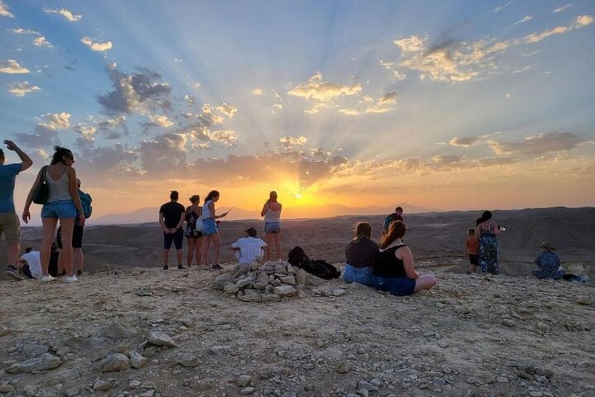 een groep mensen die op de top van een berg staan en naar de zonsondergang kijken