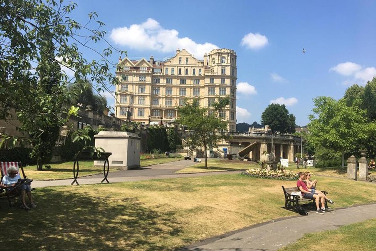 Dos personas sentadas en bancos en un parque con un gran edificio.
