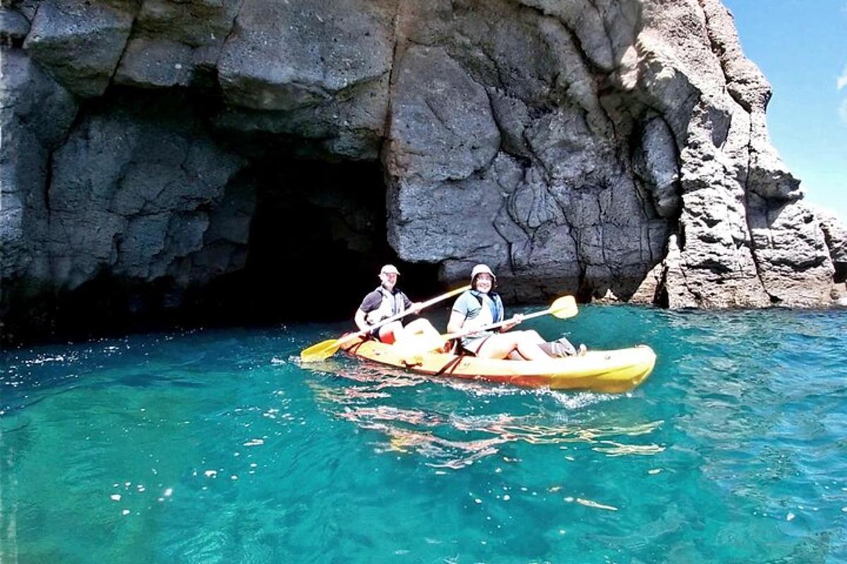 Dos personas en un kayak en el agua cerca de una cueva.