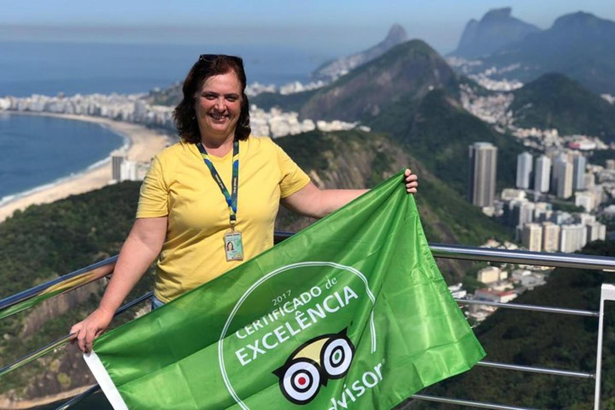 een vrouw die een groene vlieger vasthoudt op de top van een berg